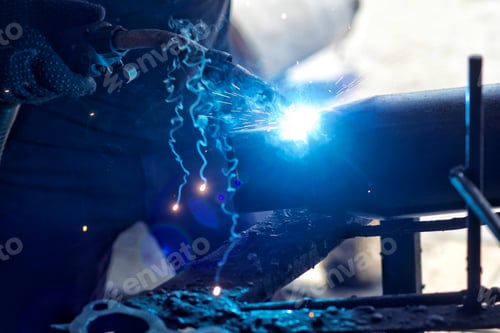 Preview: An unrecognizable industrial metalworker makes sparks fly and smoke as he welds steel