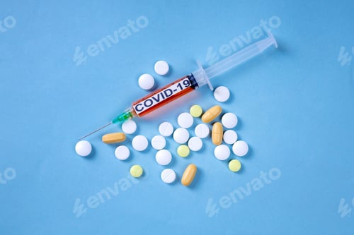 Preview: Syringe for Covid-19 vaccination aa bunch of pills on a blue background