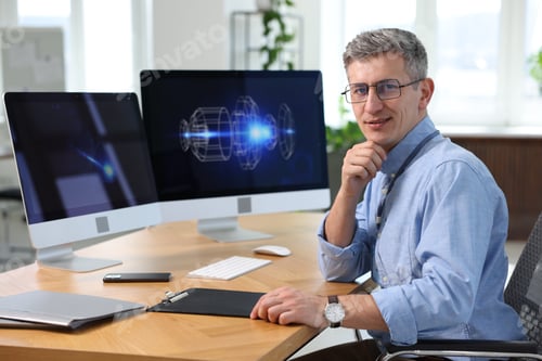 Preview: Portrait of smiling engineer at table with monitors in office