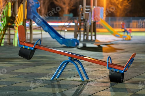 Preview: Seesaw swing in preschool yard with soft rubber flooring at night.