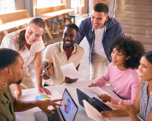 Preview: Multi-Cultural Business Team Meeting Around Desk In Modern Open Plan Office Discussing Documents
