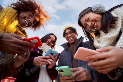 Preview: Low angle view of a smiling group of young people using mobile phone. Technology connection addicted