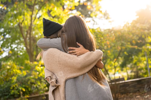 Preview: Autumn lifestyle, women friends hugging in a park in autumn at sunset