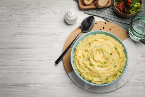 Preview: Bowl of tasty mashed potatoes with greens served on white wooden table, flat lay. Space for text