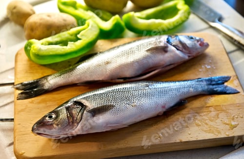 Preview: Whole fresh caught sea bass on a chopping board