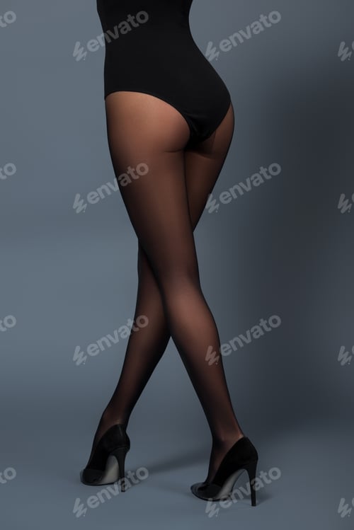Preview: Woman posing in black pantyhose and heel shoes on dark background