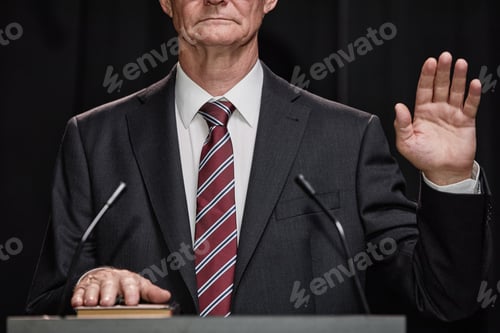 Preview: Male Politician in Suit Raising Hand Swearing to Comply with Law at Podium Indoors