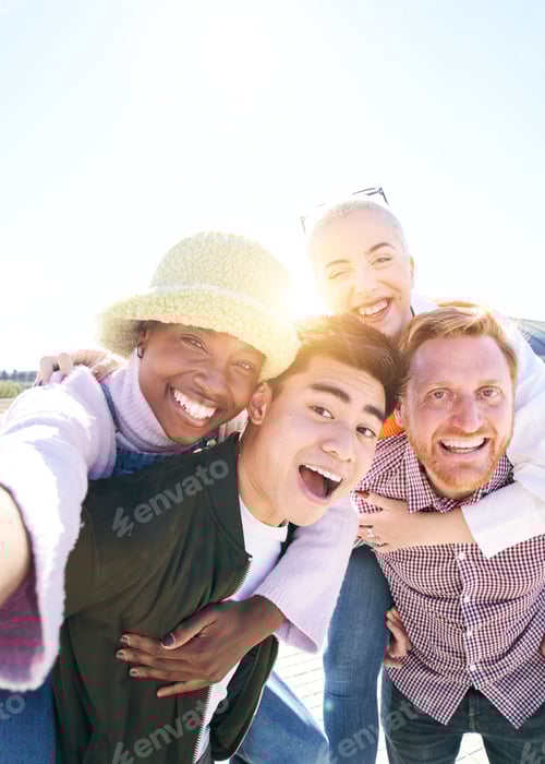 Vertical picture Piggyback friends taking smiling selfie together outdoors in a sunny day. Portrait.