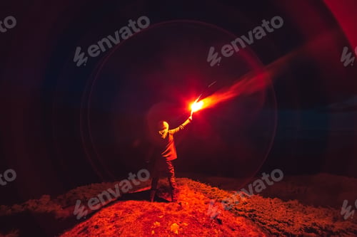 Preview: The man with a red firework stick standing on a night mountain.