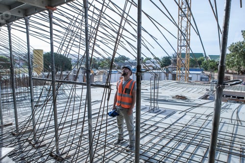 Preview: Site manager looking up at steel rod structures on construction site