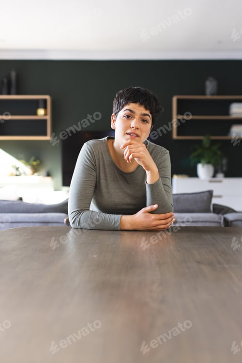 Preview: Happy biracial woman sitting at dining table having video call at home, listening, copy space