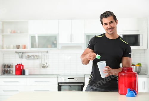 Preview: Young athletic man preparing protein shake in kitchen, space for text