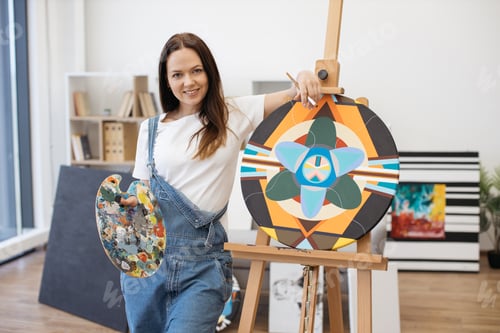 Preview: Confident artist posing on camera with palette near easel