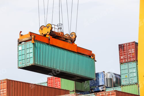 Preview: A port crane lifts a large green shipping container onto a stack