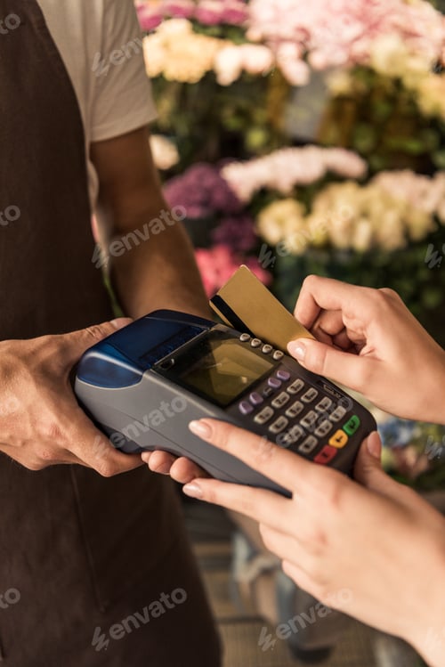 Preview: cropped image of customer paying for flowers with credit card at store