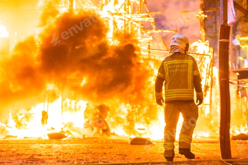 Preview: Silhouette of fireman trying to control a fire in a street during a night.