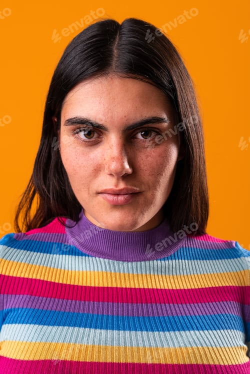Preview: Young woman with freckles posing in studio with orange background
