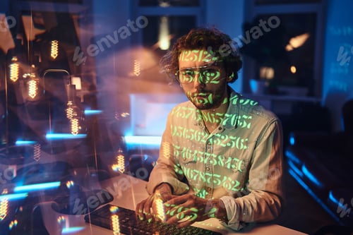 Preview: Guy in green beams works on computer in dark office room