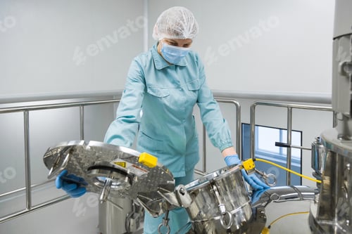 Preview: Pharmaceutical factory woman worker in protective clothing operating production line in sterile