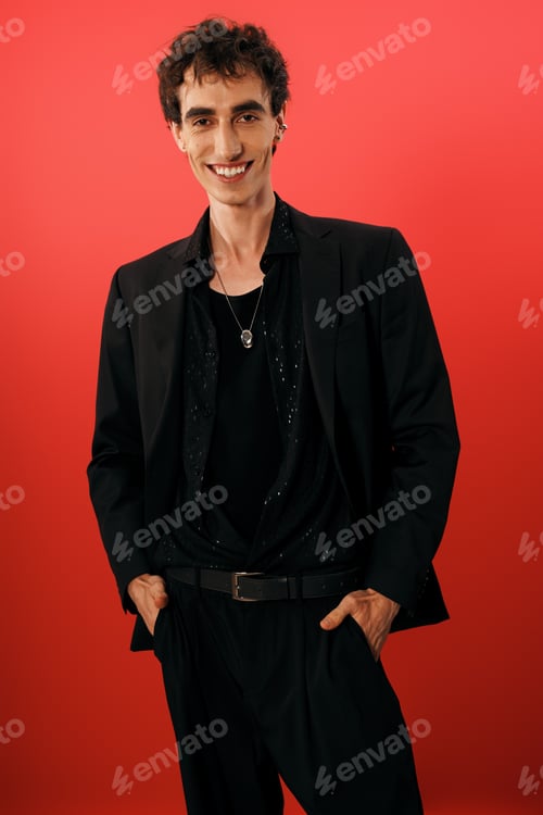 Preview: Handsome man in elegant attire poses confidently against a vibrant red backdrop