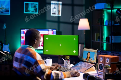 Preview: African american photo designer retouching images next to green screen on dual screens
