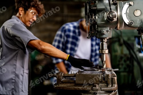 Preview: Asian worker in production plant drilling at machine.
