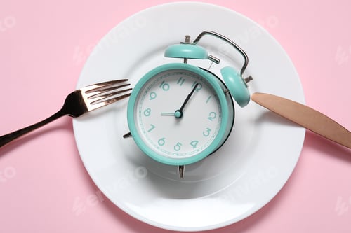 Preview: Alarm clock, plate and cutlery on pink background, flat lay