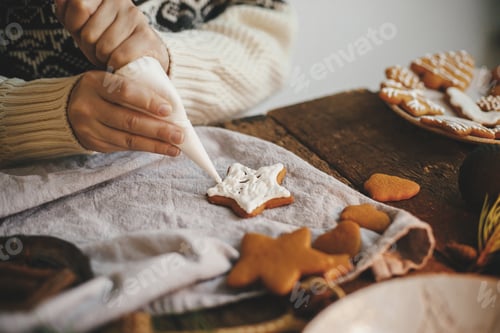 Preview: Hands decorating christmas gingerbread cookie star with frosting on rustic table. Atmospheric image