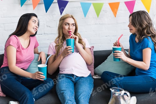 Preview: multicultural friends and pregnant woman drinking at baby-party