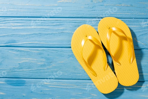 Preview: top view of yellow flip flops on wooden blue background