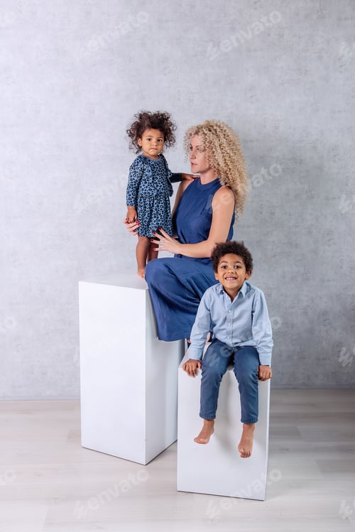 Preview: Caucasian young mother with African curls hugs African American children. Happy mixed race family