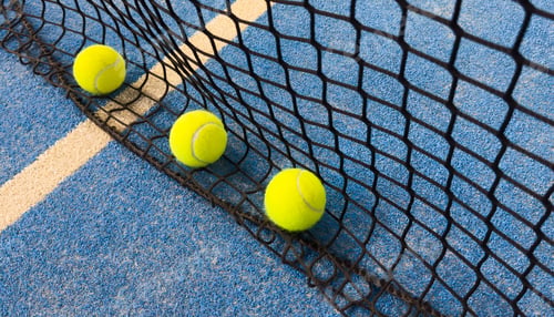 Preview: Net of a blue paddle tennis court and balls. Racket sports concept.