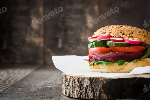 Preview: Delicious vegetarian beetroot burger with radish, cucumber and tomato on rustic wooden background