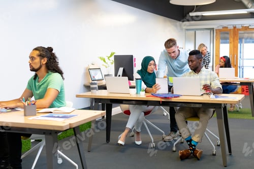Preview: Front view of diverse business people working together at desk in a modern office