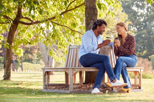 Preview: Loving Mature Couple Relaxing Sitting Together On Bench Under Tree In Summer Park With Coffee