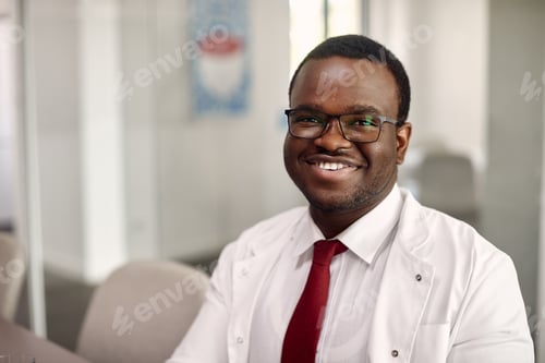Preview: Portrait of happy black doctor at medical clinic looking at camera.
