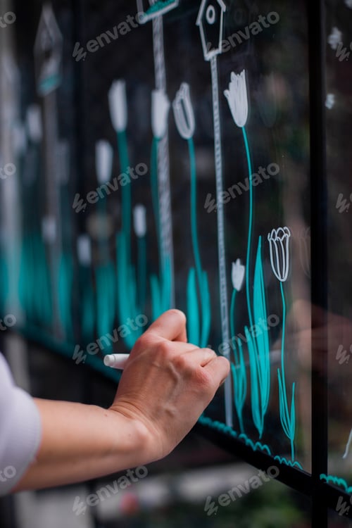 Preview: cropped photo of woman's hand drawing on glass in cafe