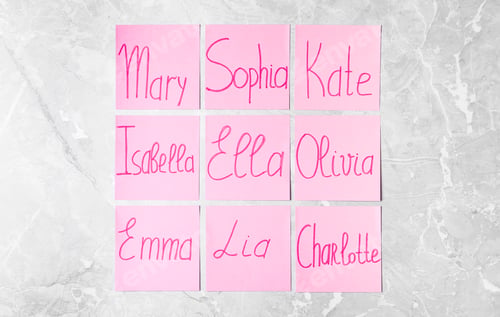 Preview: Paper notes with different baby names on grey marble table, flat lay