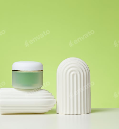 Preview: Green jar for cosmetics on a white table. Packaging for cream, gel