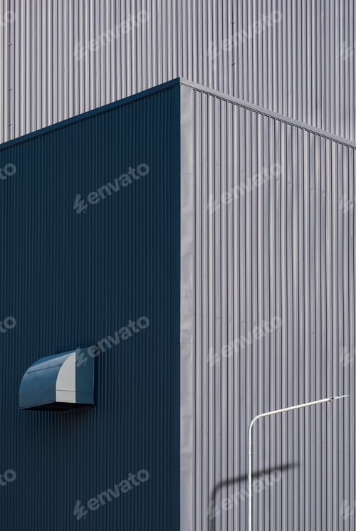Preview: Light and shadow on surface of gray corrugated metal industrial building in vertical frame