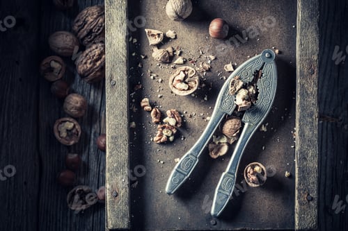 Preview: Cracked nuts and old nutcracker. Walnuts on the old table.