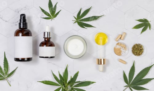 Preview: Cosmetic bottles, jar, pipette with CBD oil, capsules and tea near green cannabis leaves. Mockup
