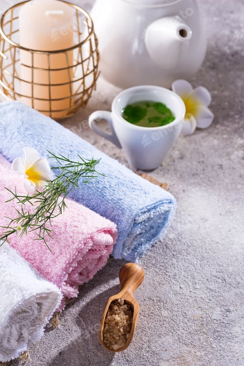 Preview: Color towels with flower, spoon of salt, on bamboo mat, bath spa treatment and green tea on stone