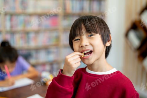 Preview: Asian boy look like Chinese enjoy with eating candy in classroom while his friend serious study