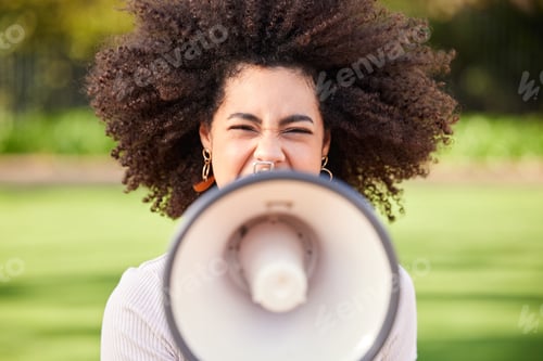 Preview: Shot of a young woman screaming into a loudspeaker while protesting in the park