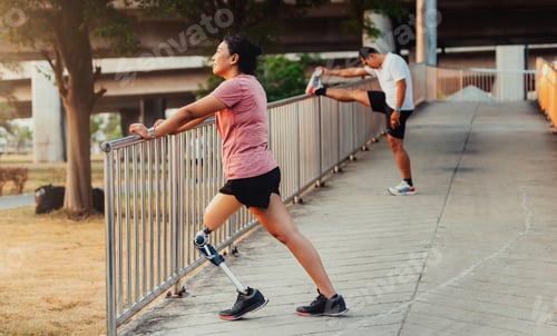 Preview: Athlete with prosthetic leg doing warm up exercise on park.