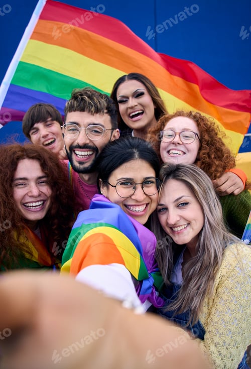 Preview: Vertical selfie of LGBT group young people celebrating gay pride day holding rainbow flag together