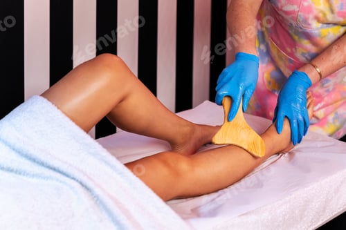 Preview: woman receiving leg massage with a wooden spatula