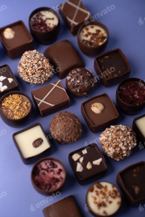 Preview: assorted artisanal chocolates and truffles on soft lavender backdrop closeup rich textures