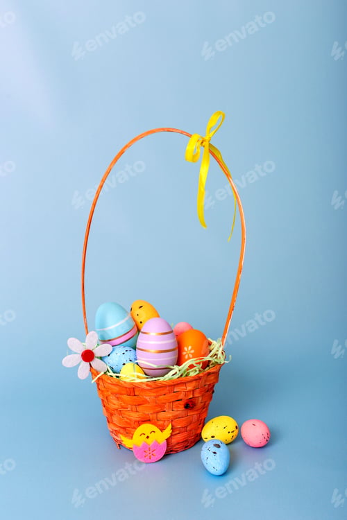 Preview: Wicker basket filled with decorative multi colored eggs on a light blue background
